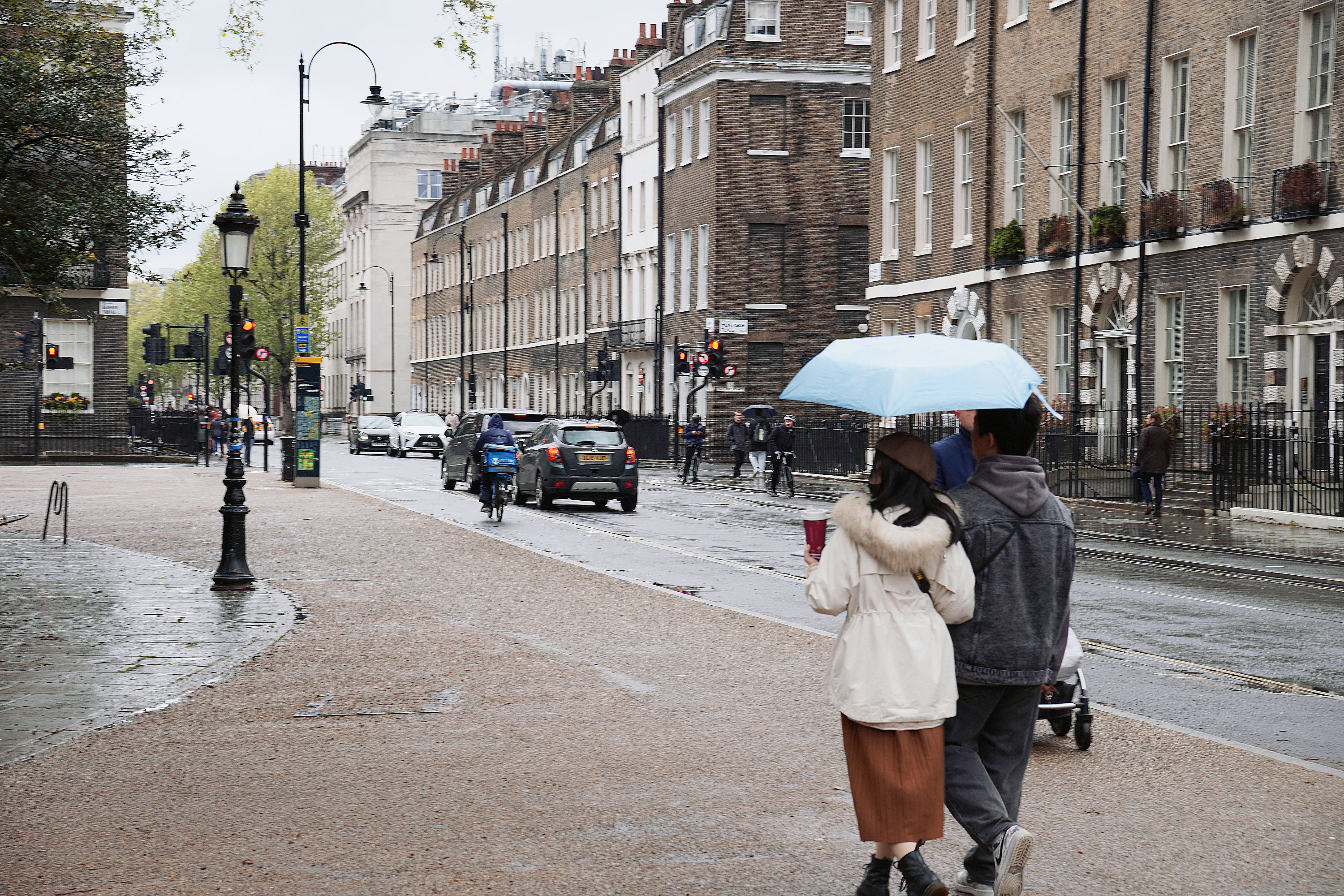 Two people sharing an umbrella on a wet London street