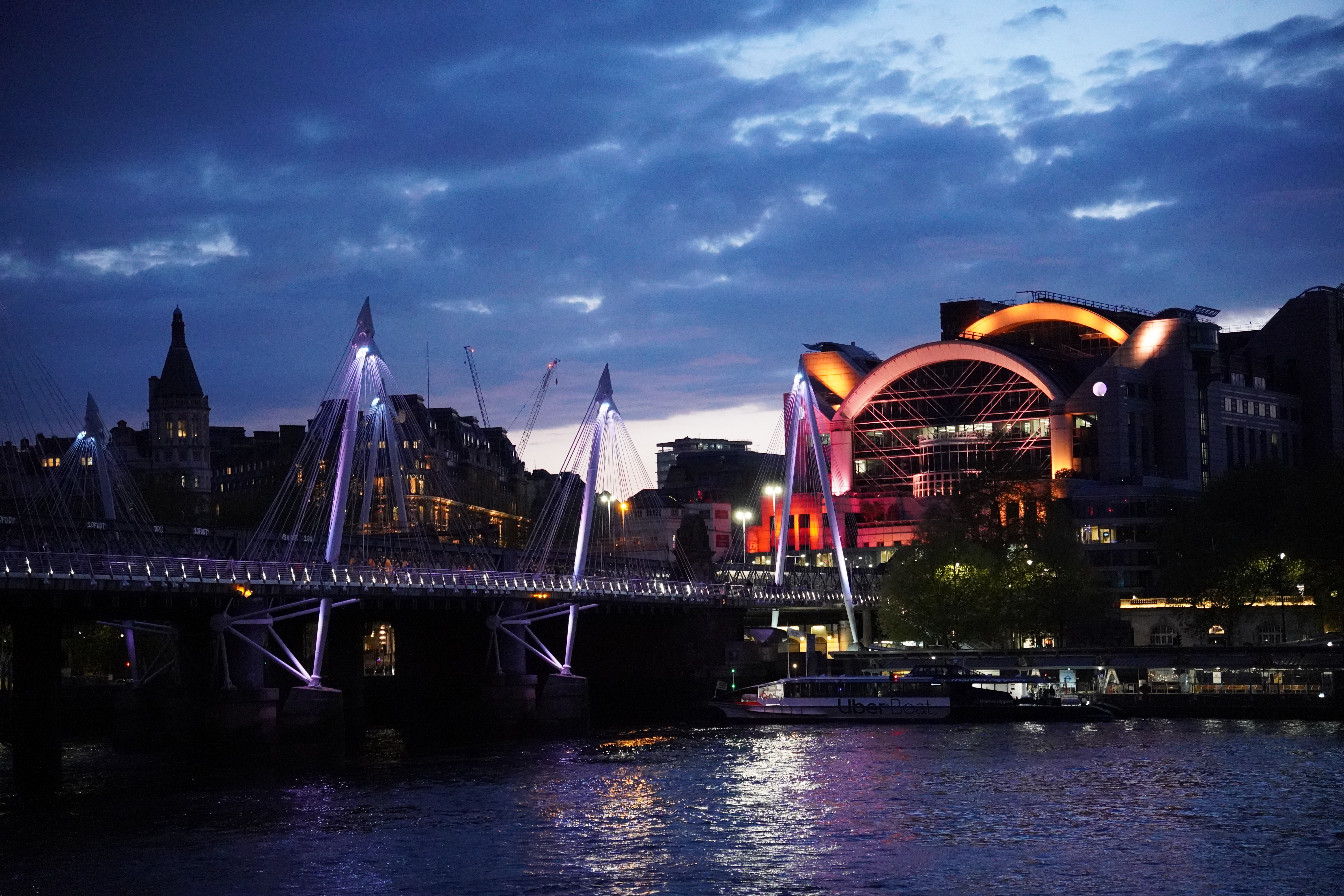 An illuminated footbridge crossing the Thames in London at night